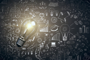 Glowing light bulb and business sketch on blackboard.