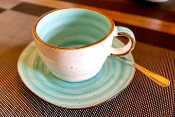 Empty aqua cup with saucer and small teaspoon served cafe table