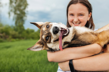 Smiling teenage girl holding a happy dog ​​in her arms, looking at the camera