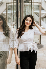 Smiling attractive woman wearing white blouse and black pants indoor