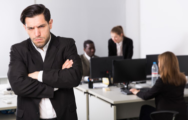 Young businessman standing in office on backround with with working colleagues