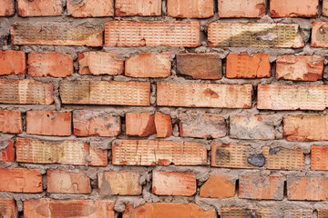 The wall is made of old non-uniform red brick of different shades, fastened with cement mortar, as...