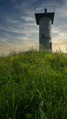 River lighthouse on a hill against the backdrop of a beautiful sunset sky