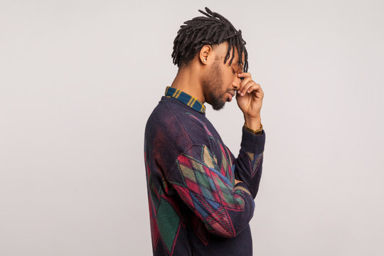 Profile portrait of deeply upset frustrated bearded african man with dreadlocks touching his face with hand, facepalm, depression. Indoor studio shot isolated on gray background