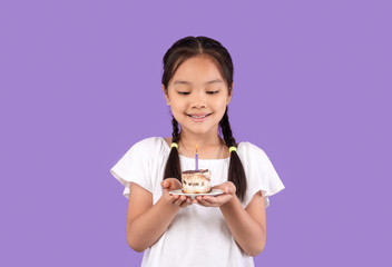 Cute Korean Girl Holding Birthday Cake Posing Over Purple Background