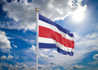 Realistic flag. 3D illustration. Colored waving flag of Costa Rica on sunny blue sky background.