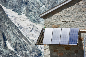 Close up of blue solar panels on wall of brick house in snowy mountains in Switzerland. Special...