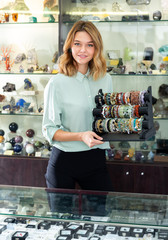 Elegant jewellery shop assistant showing colorful bracelets from semiprecious stones ..