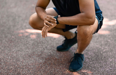 Close up view of young black jogger checking smartwatch during his morning workout