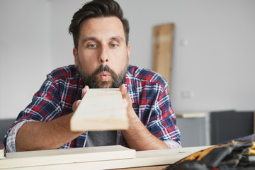 Carpenter blowing dust off a board