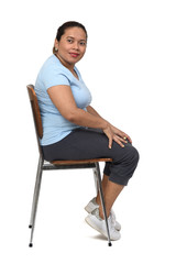 Fototapeta premium side view of a woman sitting on a chair looking at camera on white background