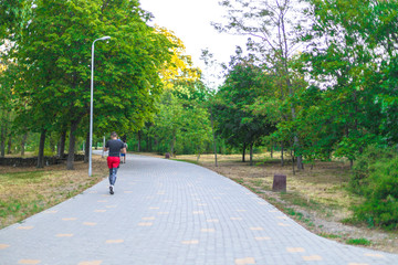 Young man doing sports and jogging in a park in the morning. Health and fitness outdoor concept.