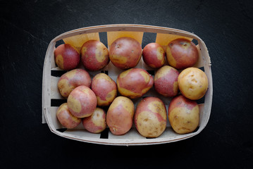 Canary islands potatoes, pink variety in a basket over dark backround (Canarian pink potatoes)