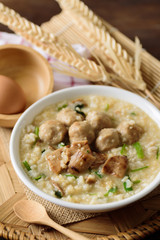 Asian food, Rice soup with meat ball, grilled mushroom and vegetable in a bowl on woven bamboo tray
