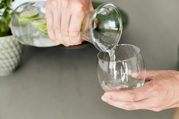 Person, die sich Wasser/Hausgemachte Limonade aus einer Karaffe in ein Glas schüttet