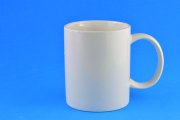 Close-up white porcelain cup, blue background and space for text