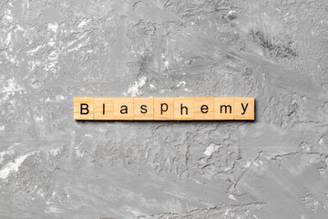BLASPHEMY word written on wood block. BLASPHEMY text on cement table for your desing, concept