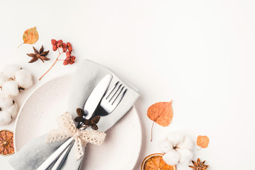 Thanksgiving autumn background. Plate with Cutlery and napkin decorated with autumn leaves, berries and spices. Top view.