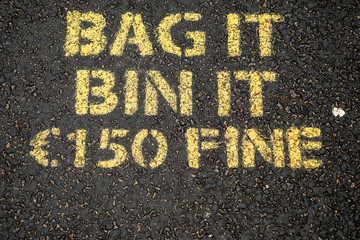 Yellow sing on a dark asphalt to dog owners to clean up dog poo. Bag it, bin it. 150 euro fine.