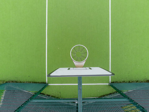 Aerial drone view on a green basketball court. Plastic floor surface with white marking. White board. Green mesh fence. Outdoor.