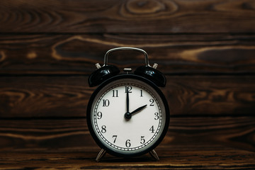 Clock on a wooden background. The clock shows the time of two o'clock in the afternoon. Clock showing the time of two o'clock in the morning. An image of a retro clock showing 02:00 pm/am. Copy space