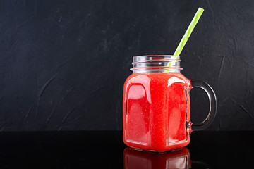 Fresh delicious watermelon smoothie with ice on dark background
