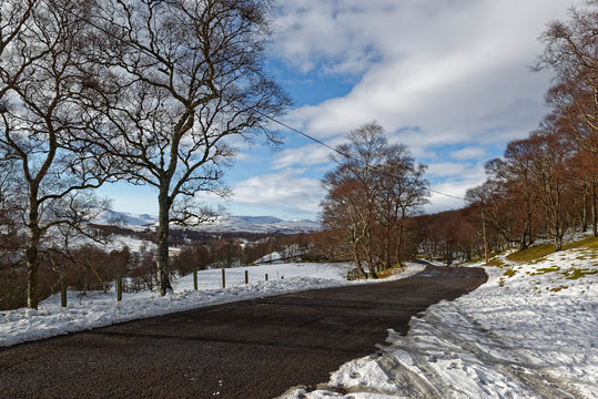 The road to Tarfside and Glen Esk in the Angus Glens of Scotland on a Winters afternoon in February, with long shadows cast by the watery sun.