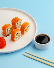 sushi rolls on a white plate on a blue background.