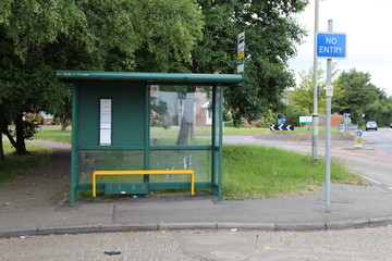 A green  bus shelter on the corner of a road in Hemel Hempstead, Hertfordshire, England.
