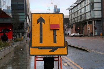 A temporary road sign set up on a footpath to indicate a lane closure for drivers in Manchester, England.
