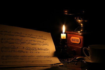 Musical notes and coffee grinder in candlelight on a black background