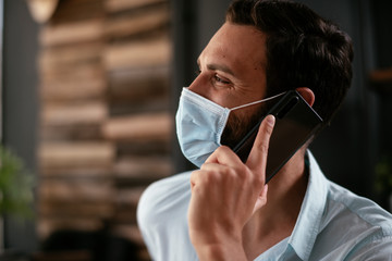 Handsome businessman with medical mask. Young man talking to the phone in office..
