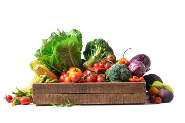 Organic vegetables and greens in a wooden box on a white isolated background.