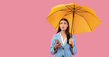 Portrait of unhappy young girl holding yellow umbrella