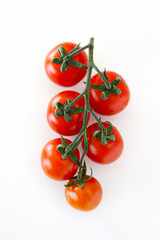 Branch of beautiful juicy organic red cherry tomatoes on white background. Top view of shiny polished glossy vegetables. Clean eating concept. Vegetarian vegan summer detox diet. Copy space, flat lay.