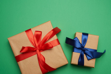 boxes wrapped in brown paper and tied with a red and blue bow, gifts on a green background