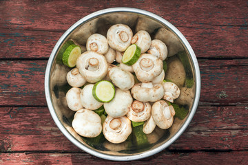 Raw mushrooms champignons in a bowl on a wooden table