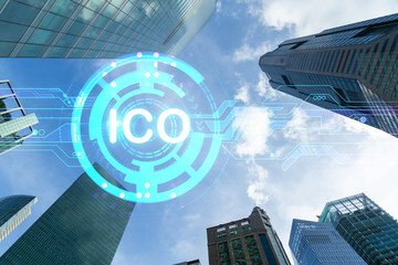 ICO icon hologram on low, wide angle view of glass and steel contemporary skyscrapers in financial downtown. The concept of success in initial coin offering. Double exposure.