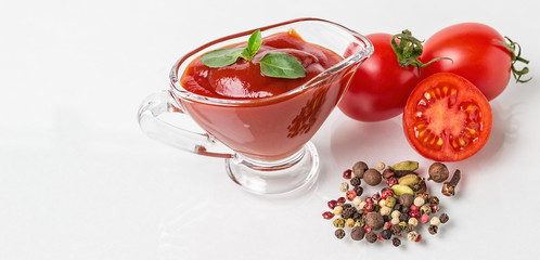 Cherry tomatoes, spices and a glass sauceboat with ketchup on a white background. Seasonings, tomato sauce and tomato