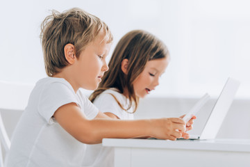 selective focus of concentrated boy and girl using laptops at home