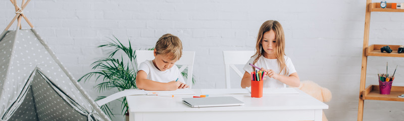 horizontal image of brother and sister in pajamas drawing with felt pens at table near kids wigwam © LIGHTFIELD STUDIOS