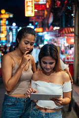 Girls in Bangkok at night looking at digital tablet stock photo