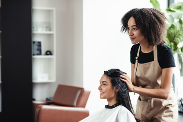 Young brunette enjoying beauty procedures at hairdresser salon - obrazy, fototapety, plakaty