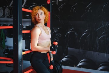 Fototapeta na wymiar Close up of sporty woman lifting dumbbell in gym.