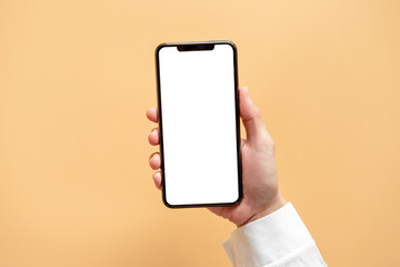 Fototapeta na wymiar Smartphone mockup. Close up hand holding black phone white screen on yellow background. Mobile phone frameless design concept.