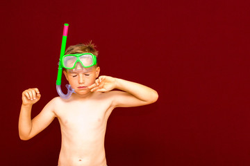 The boy after diving advertises diving snorkeling mask on the red background. summer concept