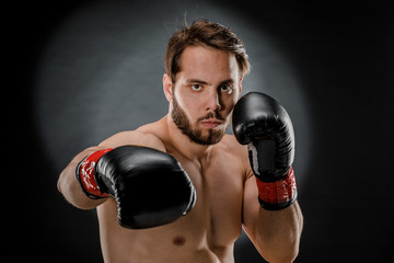 A man in Boxing gloves. A man Boxing on a black background. The concept of a healthy lifestyle