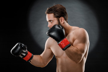 A man in Boxing gloves. A man Boxing on a black background. The concept of a healthy lifestyle