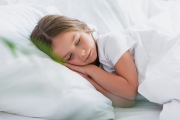 Obraz na płótnie Canvas selective focus of girl sleeping while lying on white bedding
