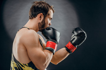 Naklejka na ściany i meble A man in Boxing gloves. A man Boxing on a black background. The concept of a healthy lifestyle